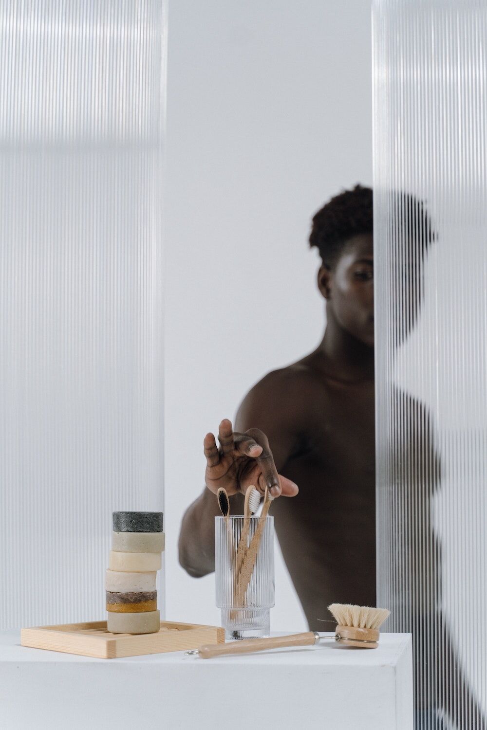man in the shower picking up a toothbrush