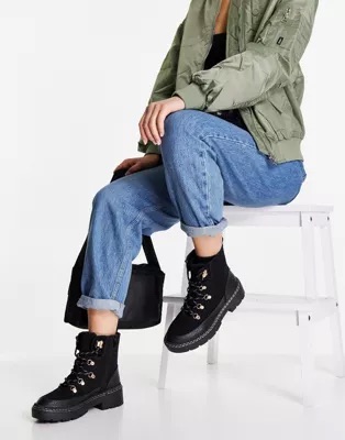 A green bomber jacket, denim jeans, a black shoulder bag and black hiker boots.