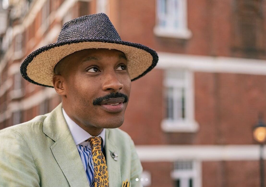 man wearing a suit and hat, grinning away from the camera