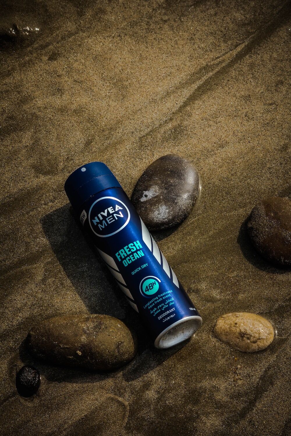 Spray deodorant bottle leaning against rocks, low lighting