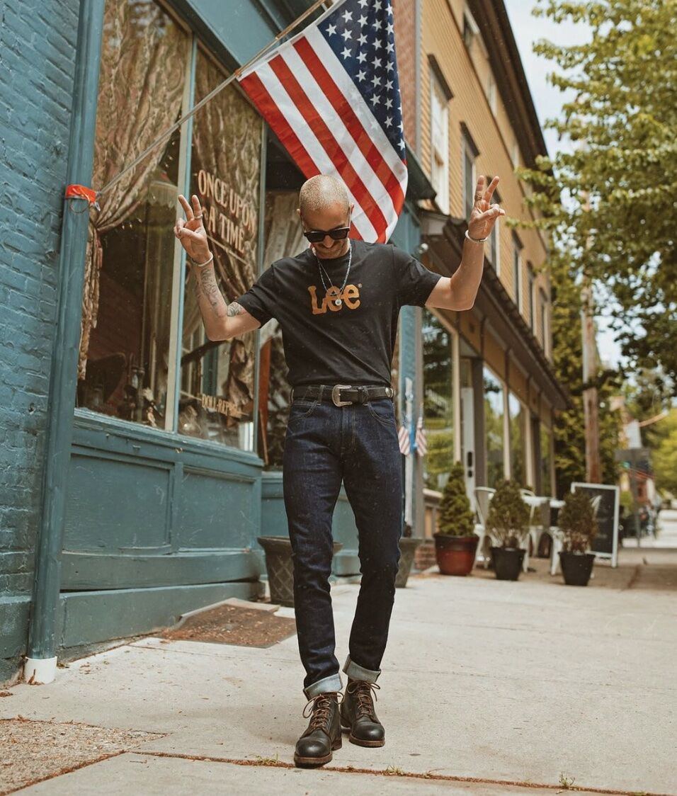 man with his hands up with peace signs wearing a western belt